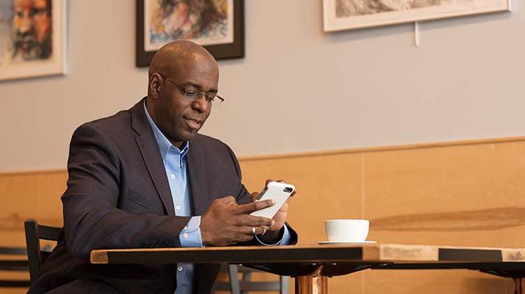 A man works on his phone at a cafe.