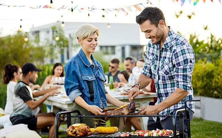 Man serves food from grill to friend.