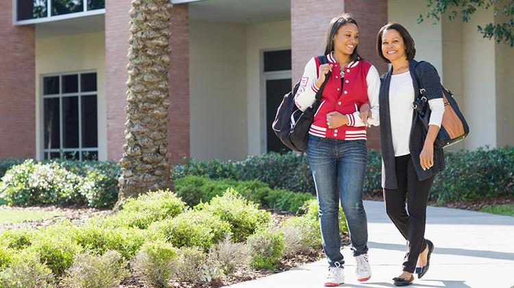 Mother and daughter walk arm-in-arm on a college tour.