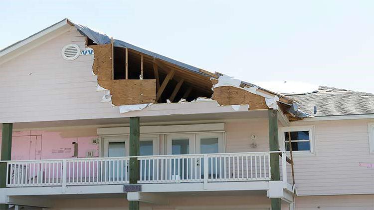 House with part of roof missing from hurricane damage.